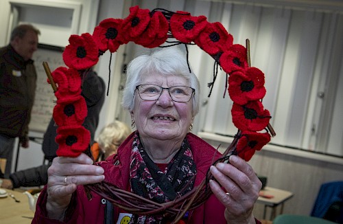 Tea party guest holding their crafted poppy wreath