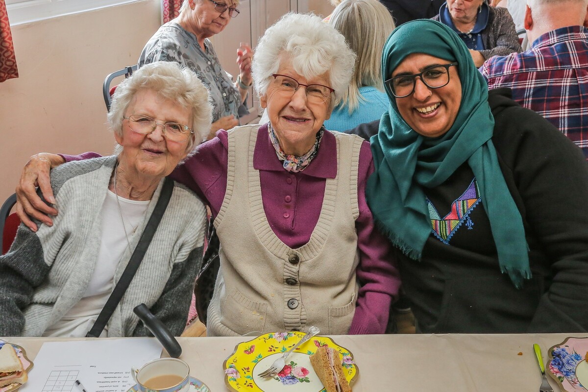 Three people sat at a table looking into the camera