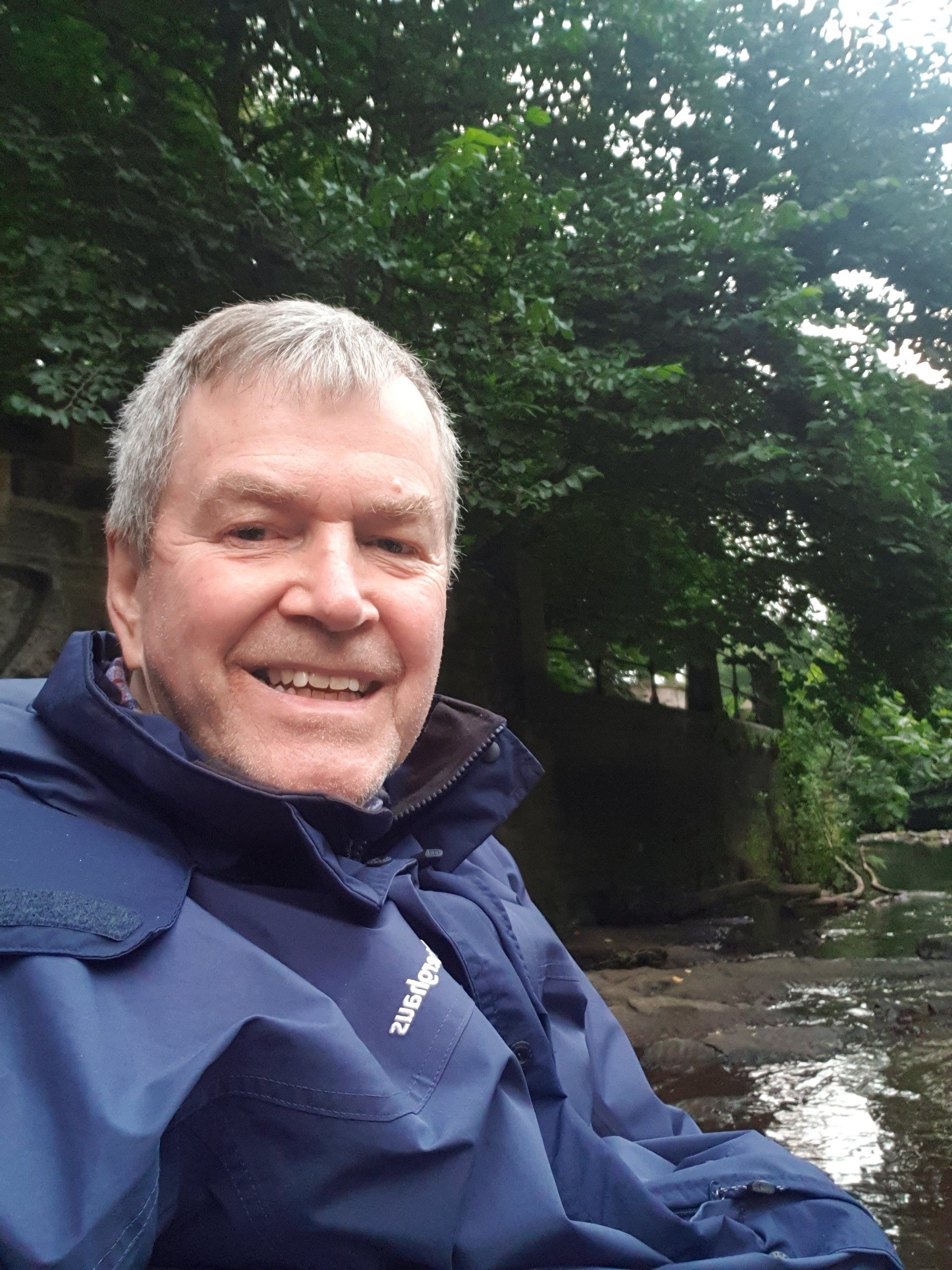 Gordon standing in front of a tree with water behind him