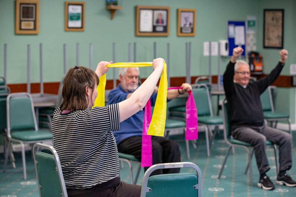 A group of people with ribbon doing a gentle exercise activity group